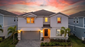 A two-story residential house with a garage, a front porch, and a well-maintained lawn. - 9-bedrooms ~ 25 Mins To Parks ~ Pool, Water Slides Hot Tub, Sauna, Mini Golf! (Davenport)