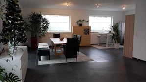 Een moderne keuken met een eethoek, grote ramen en potplanten.