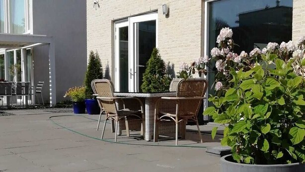 Een modern gebouw met een terras, zitplaatsen buiten en potplanten.