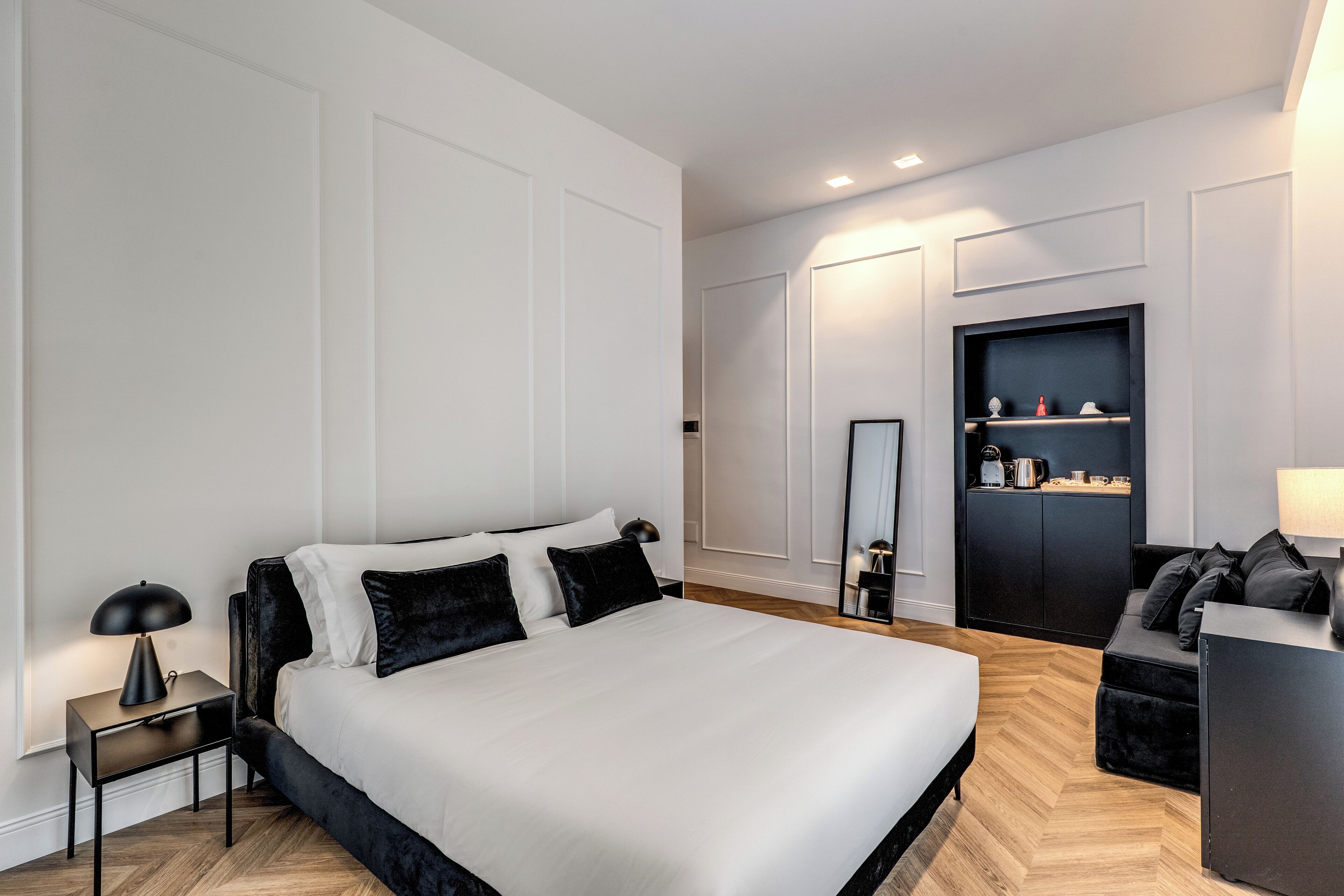 A modern bedroom with a large bed, a nightstand, a dresser, and a mirror.