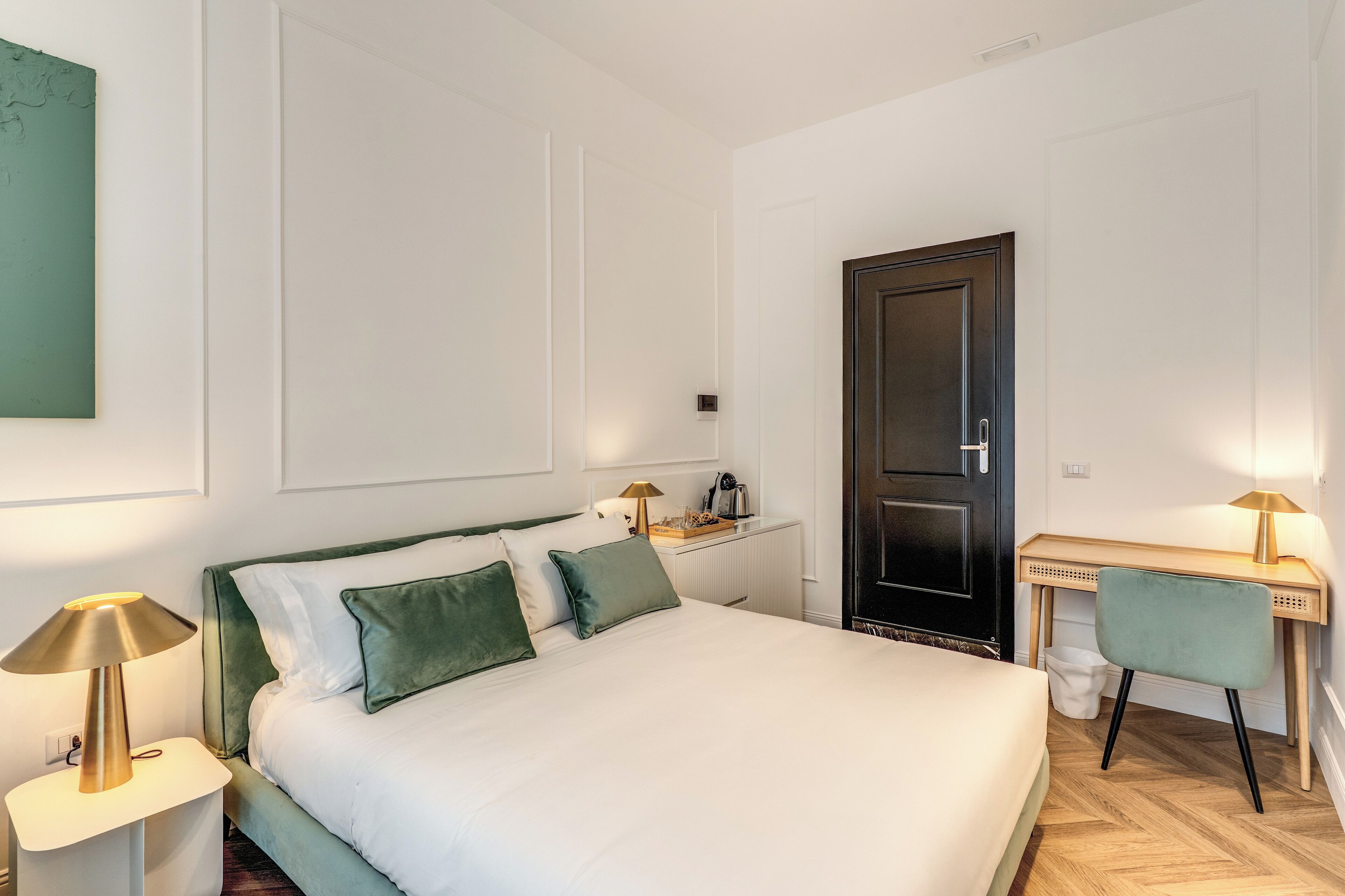 A neatly arranged bedroom with a bed, bedside tables, a desk, and a chair.