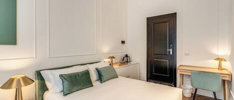 A neatly arranged bedroom with a bed, bedside tables, a desk, and a chair.
