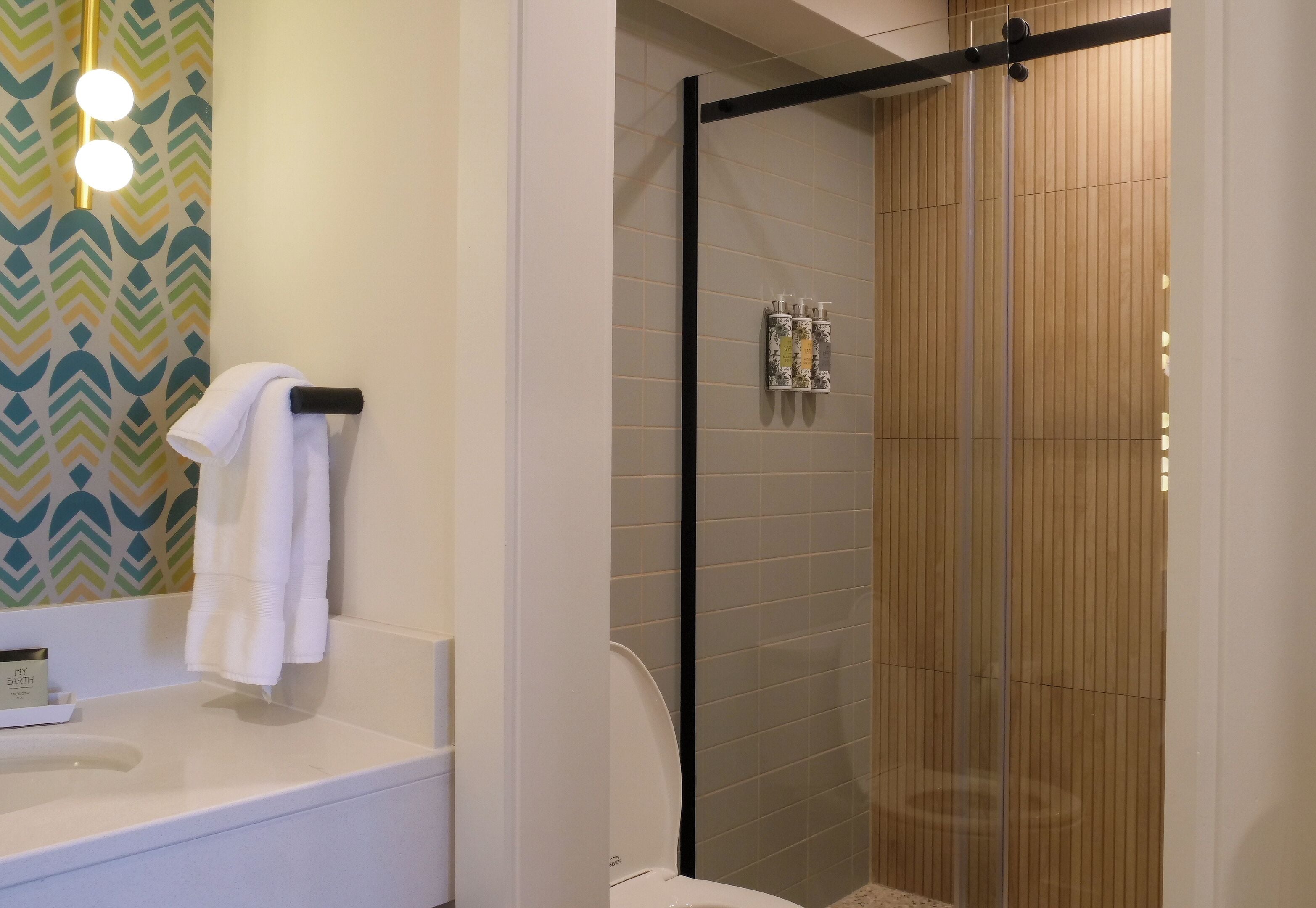 A modern bathroom with a glass-enclosed shower, a white sink, and a towel rack.