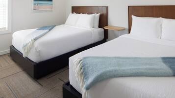 Two beds with wooden headboards, white bedding, and a blue throw blanket on one bed.