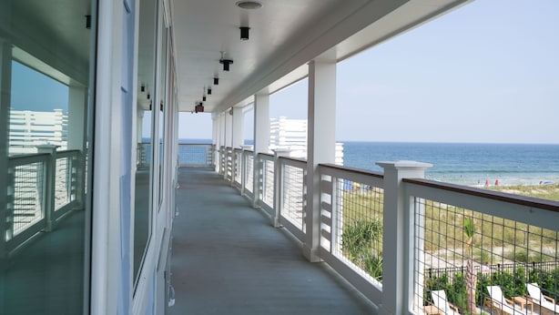 A balcony with a view of the ocean, white railings, and a clear sky. - Oceaneer (Carolina Beach)