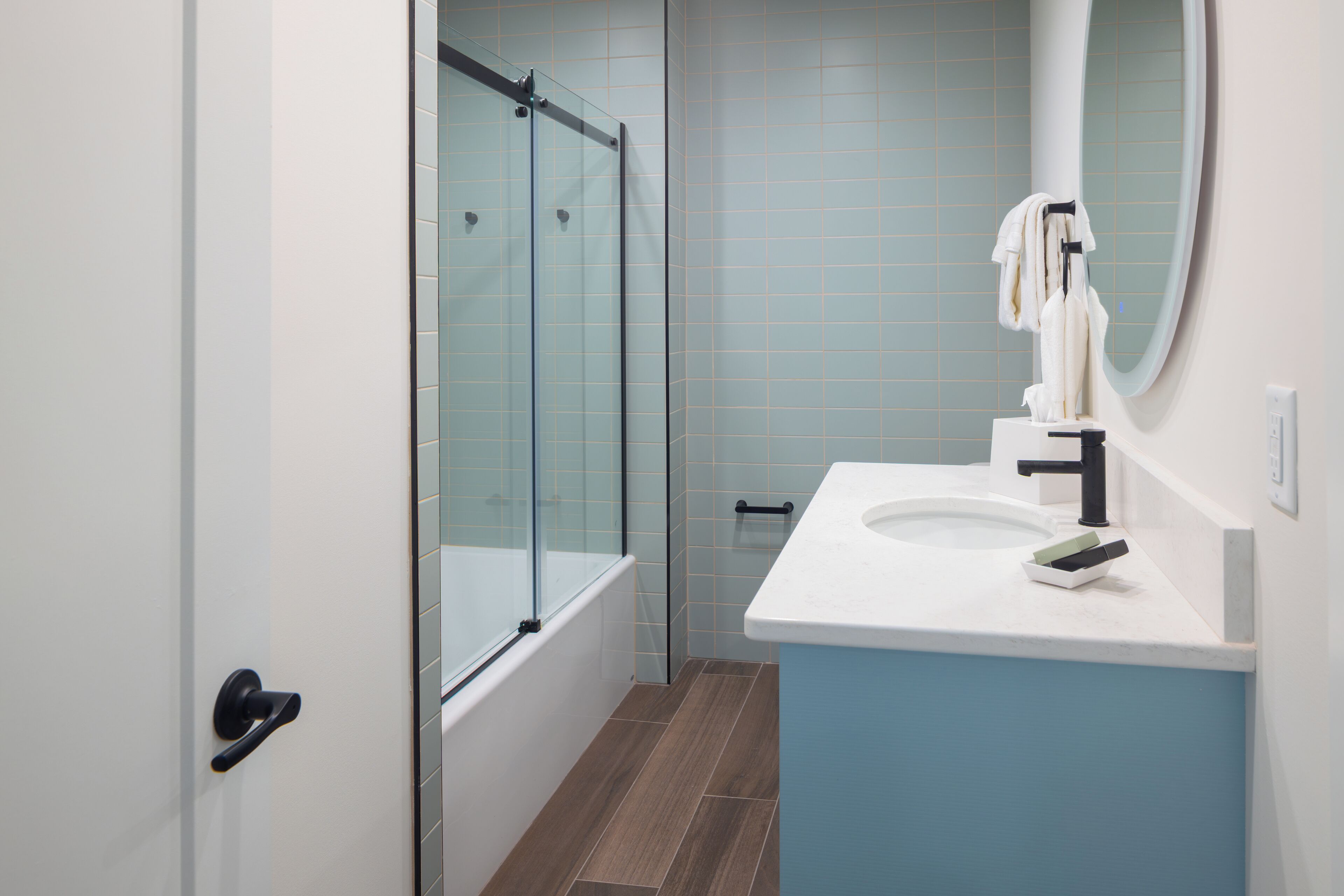 A modern bathroom with a glass shower enclosure, a white sink with a black faucet, and a mirror above the sink.