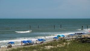 A beach with waves, umbrellas, and people. - Oceaneer (Carolina Beach)