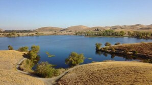 A serene lake surrounded by hills and sparse vegetation.