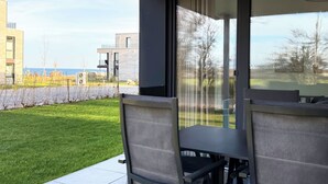Eine Terrassenfläche mit Tisch und Stühlen, mit Blick auf einen gepflegten Rasen und eine Wohngegend.