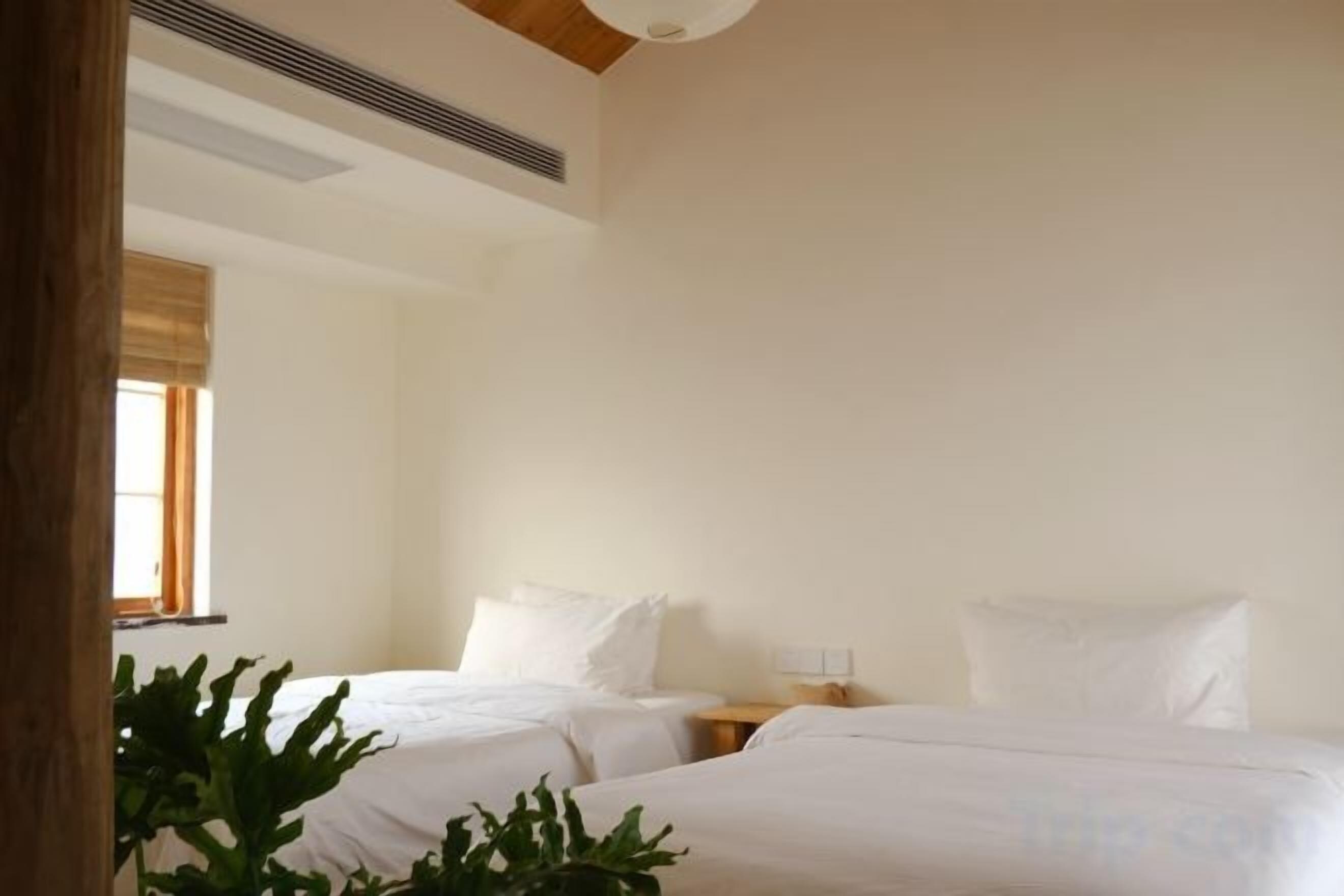 A hotel room with two beds, a bedside table, and a window with curtains.