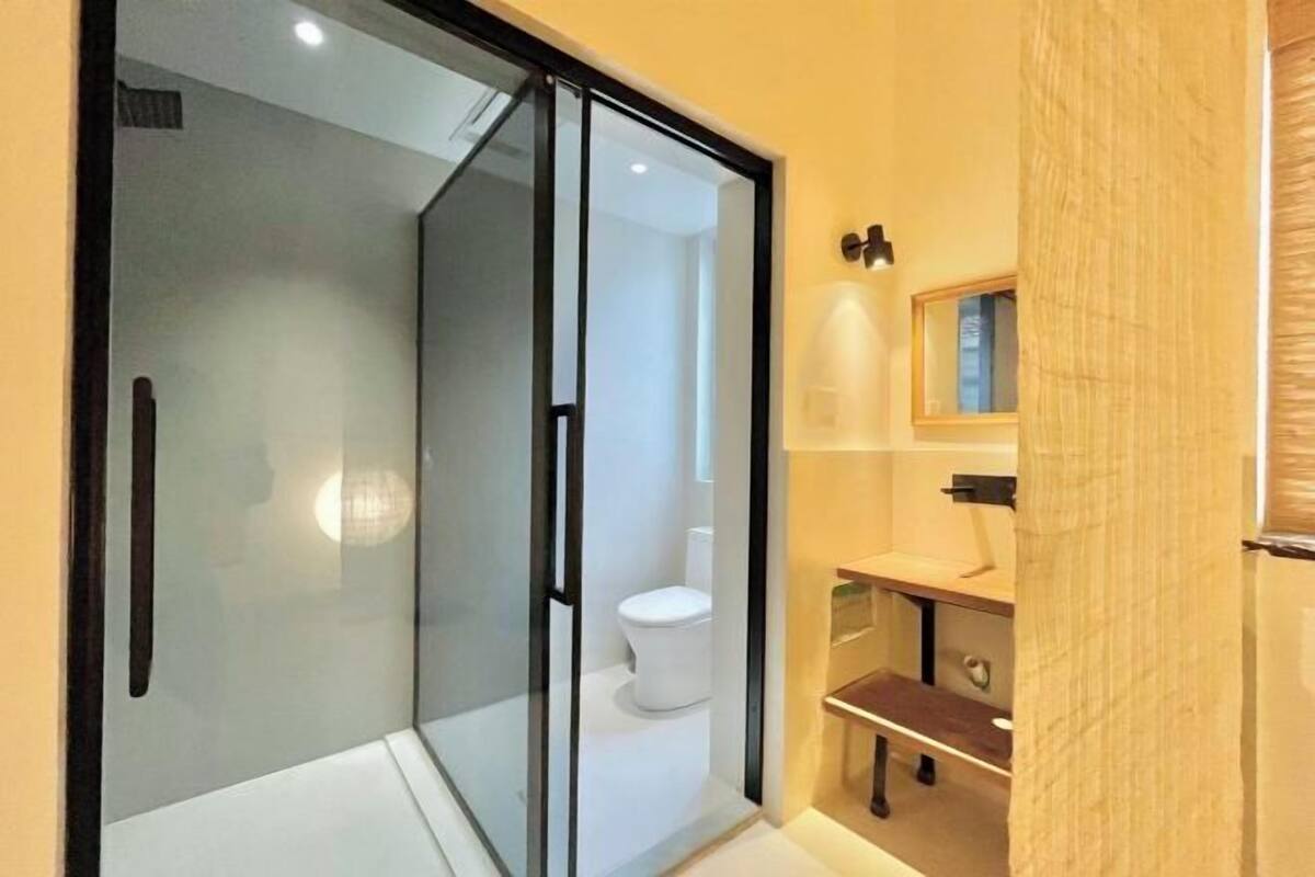 Een moderne badkamer met een douchecabine van glas, een toilet en een wastafel met spiegel.