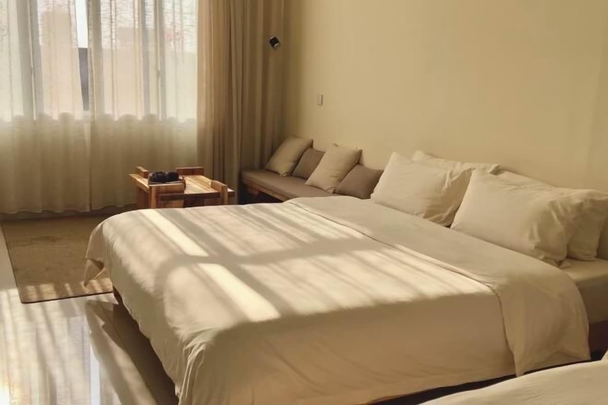 A bedroom with a large bed, a small table, and a sofa.