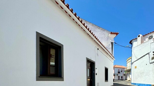 A narrow street with a white building featuring a small window and a door. - Akonxego&C.ia. Mourão - Capital of Alqueva. ☀️. (Mourão)