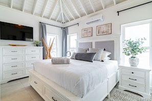 Un dormitorio con cama, televisión, cómoda y ventana.