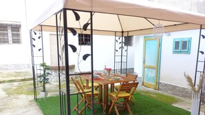 A covered outdoor dining area with a table and chairs, surrounded by a metal fence with leaf designs. - R&R House 5' walk from the Tower! Private interior courtyard !!! (Pisa)