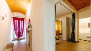 A hallway with a wooden floor, a red curtain, a small stool, and a mirror on the wall. - R&R House 5' walk from the Tower! Private interior courtyard !!! (Pisa)