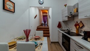 A modern kitchen with a dining area, featuring a wooden staircase leading to a living area. - R&R House 5' walk from the Tower! Private interior courtyard !!! (Pisa)