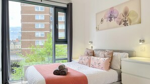 A bedroom with a large window, a bed with a pink blanket, and a wall-mounted artwork. - Sleek 3-bedroom flat with life in Southward, Bourough near The Shard (London)