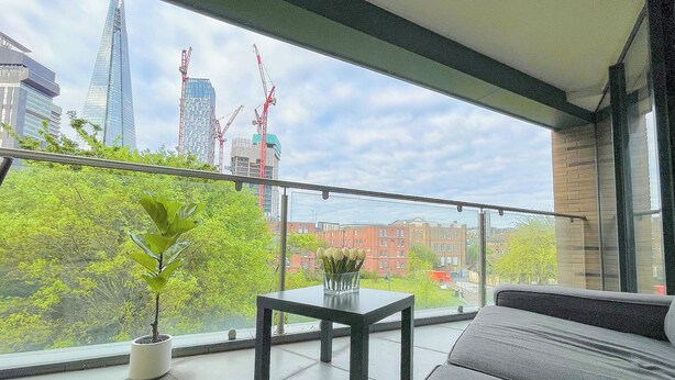 A balcony with a view of a cityscape, including a tall building under construction. - Sleek 3-bedroom flat with life in Southward, Bourough near The Shard (London)