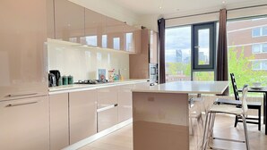A modern kitchen with a large island, stainless steel appliances, and a view of the city through the window. - Sleek 3-bedroom flat with life in Southward, Bourough near The Shard (London)
