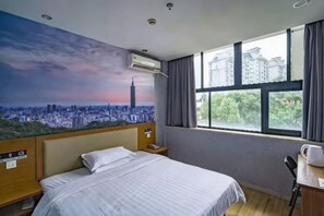 A hotel room with a cityscape mural, a bed, a desk with a chair, and a window with curtains. - Hammerhams Hotel Shanghai (Songjiang University Town) (Shanghai)