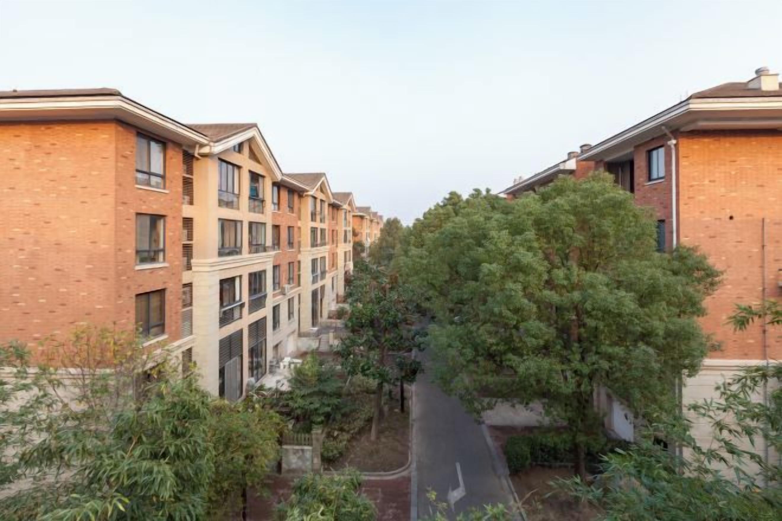 A row of brick apartment buildings with a central tree-lined street.