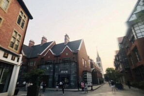 A street view with a building that has a traditional architectural style, featuring a prominent entrance and a large window. - Hammerhams Hotel Shanghai (Songjiang University Town) (Shanghai)