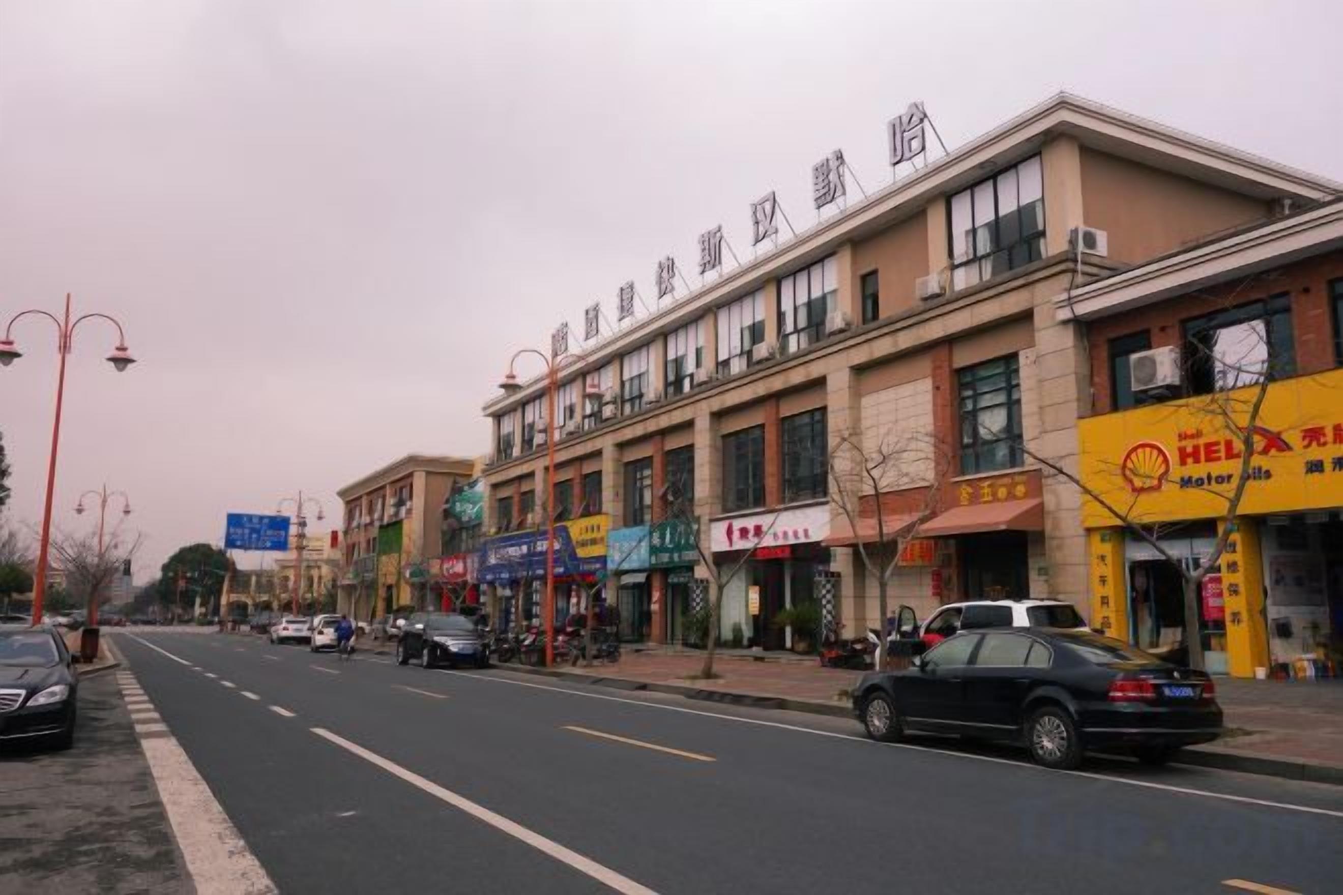 A street with buildings, shops, and parked cars.