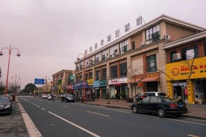 A street with buildings, shops, and parked cars. - Hammerhams Hotel Shanghai (Songjiang University Town) (Shanghai)