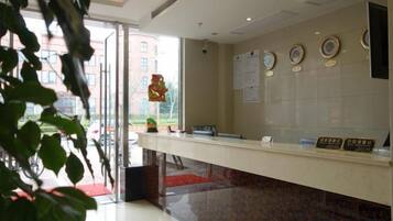 A reception desk with a glass partition, a red carpet, and a wall with circular plaques.