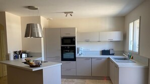 A modern kitchen with a central island, built-in oven, and a large window providing natural light. - Rasteau, vacation villa with 3 bedrooms and heated pool (Rasteau)