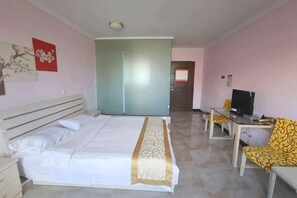 A bedroom with a bed, a desk with a chair, a television, and a door leading to another room. - Mingxing Hotel (Shanghai)