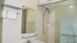 A bathroom with a glass-enclosed shower, a white sink, and a mirror above the sink. - Mingxing Hotel (Shanghai)
