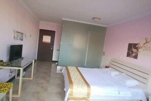 A hotel room with a bed, a desk, a television, and a door leading to another room. - Mingxing Hotel (Shanghai)