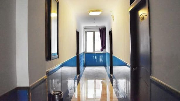 A hotel hallway with a blue and white color scheme, a reflective floor, and a door with a light fixture. - Mingxing Hotel (Shanghai)