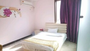 A bedroom with a bed, a nightstand, a wall-mounted air conditioner, and a window with purple curtains. - Mingxing Hotel (Shanghai)