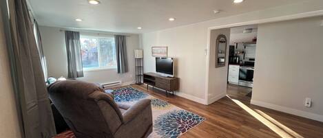 A modern living room with a large sofa, a flat-screen TV, and a patterned rug.