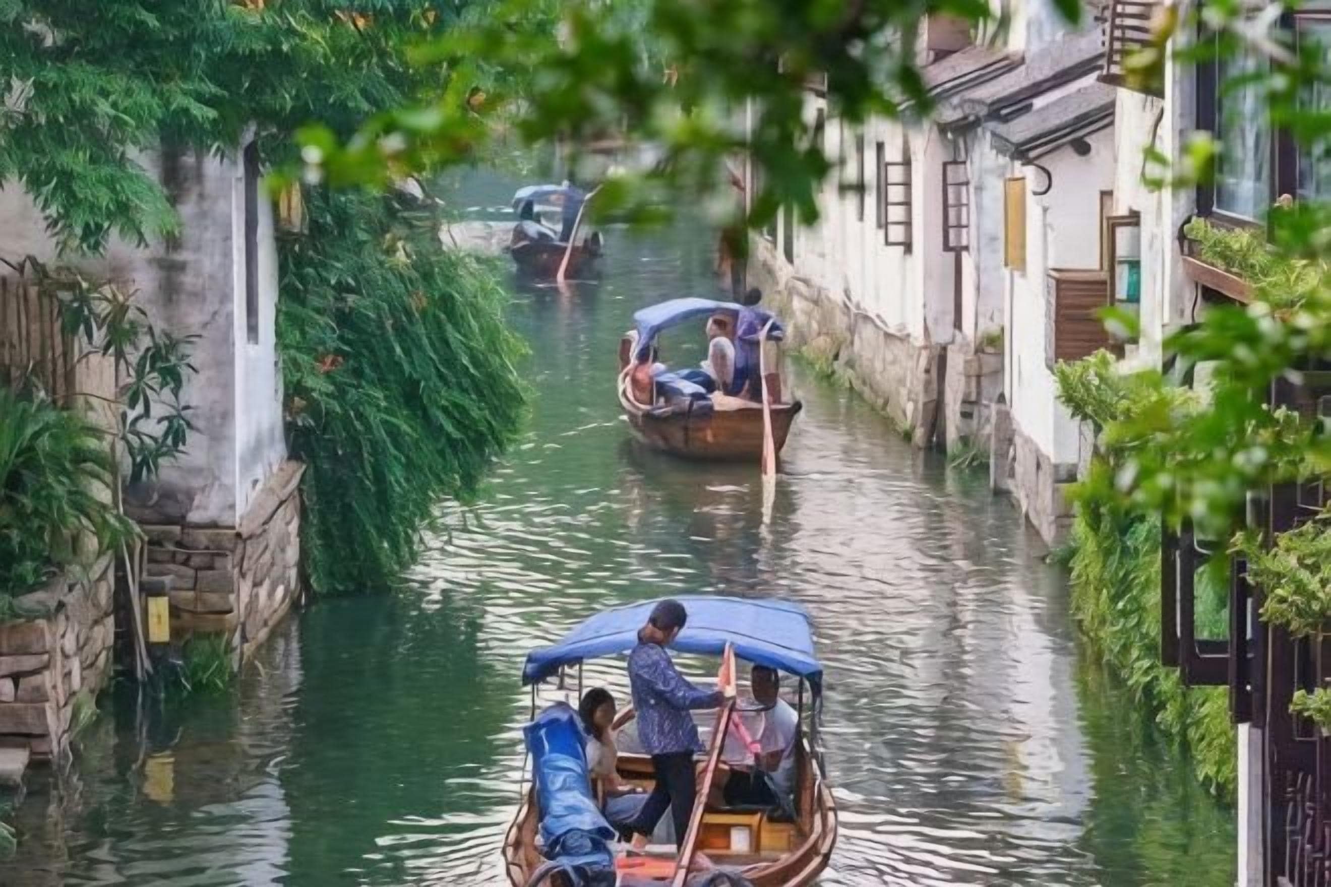 Un estrecho canal con barcos tradicionales, muros de piedra y vegetación.