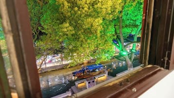 A view of a river with boats and trees illuminated by green lights.