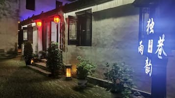 A traditional building with a signboard, potted plants, and a brick pathway.
