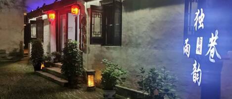 A traditional building with a signboard, potted plants, and a brick pathway.