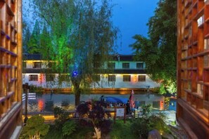 A courtyard with a water feature, a building with traditional architecture, and a view through a wooden lattice. - Duyun Yuxiang Inn (Kunshan)