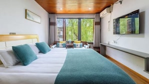 Ein Hotelzimmer mit Bett, Fernseher und Blick auf Grün.