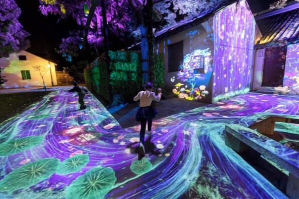 A nighttime outdoor area with illuminated pathways and a projection on a building wall. - Duyun Yuxiang Inn (Kunshan)