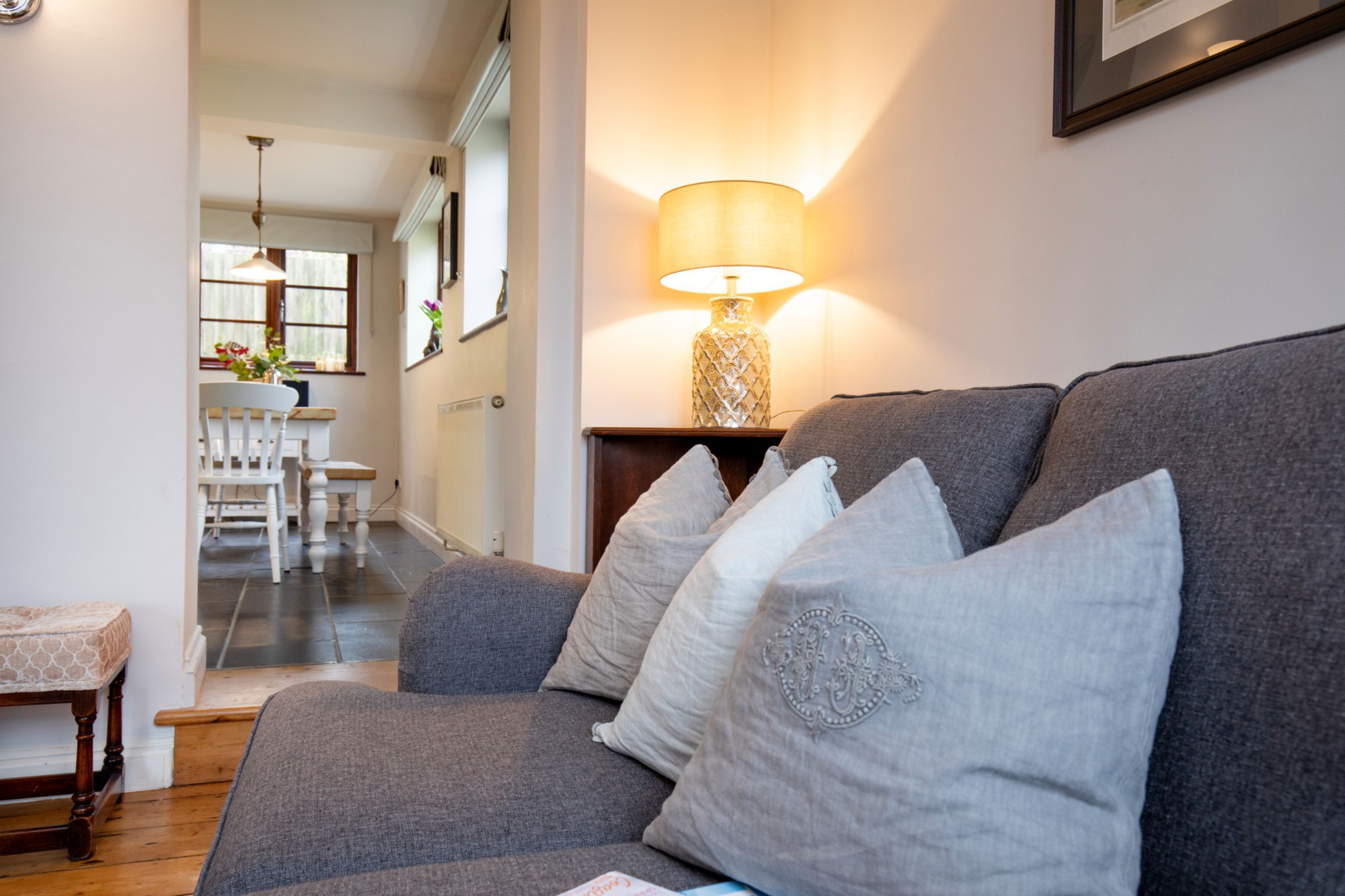 En stue med en grå sofa, hvide puder og en bordlampe.