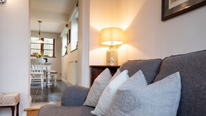 Un salon avec un canapé gris, des coussins blancs et une lampe de table.