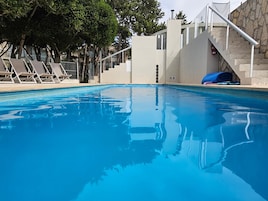 A swimming pool with lounge chairs and a staircase leading to an upper level.