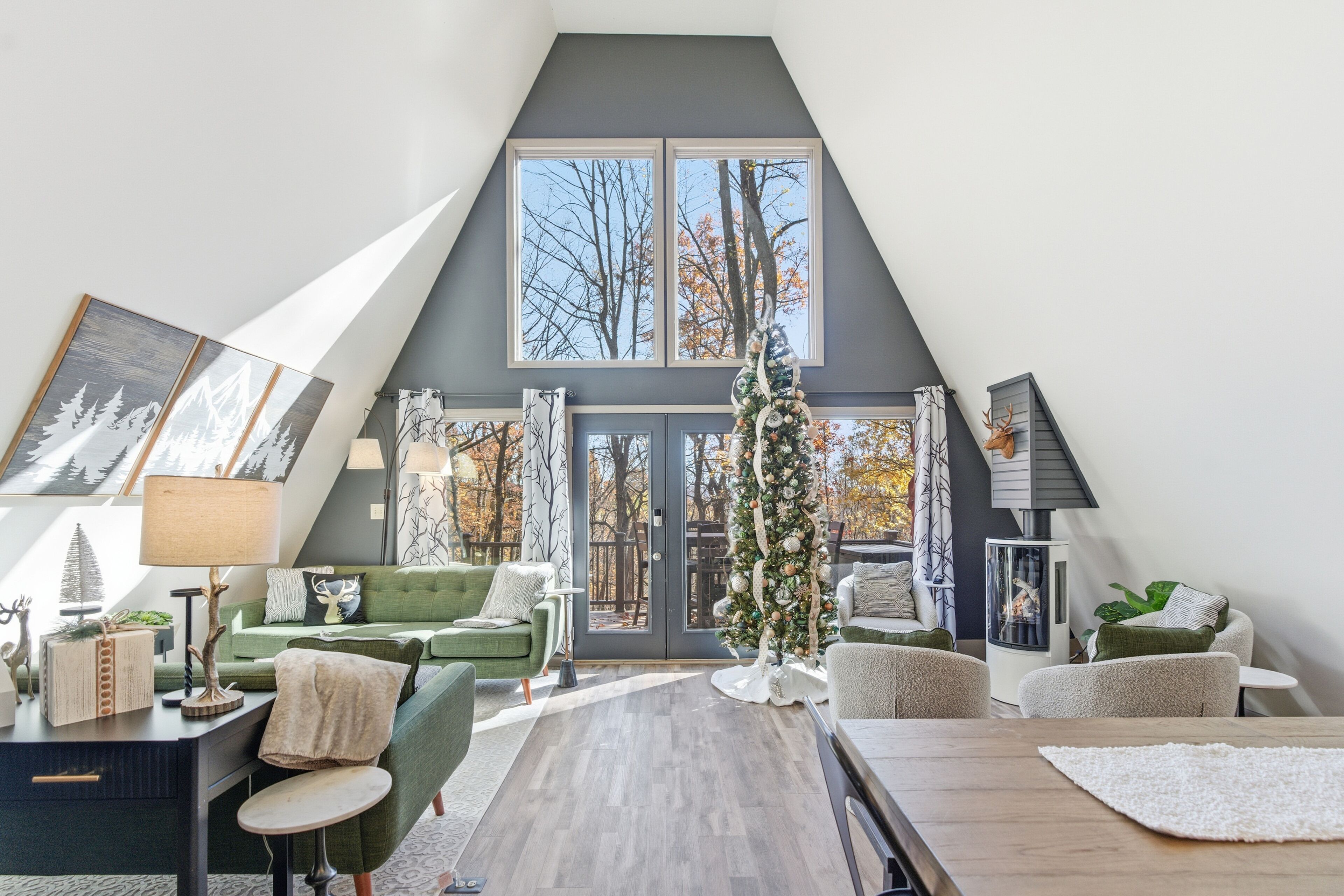 A modern loft-style living room with a large window, a fireplace, and a Christmas tree.