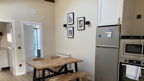 A kitchen with a wooden table and bench, a refrigerator, and an oven. - Loli's Attic (Luarca)