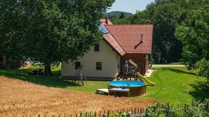 A house with a red-tiled roof, a wooden deck, and a swimming pool.